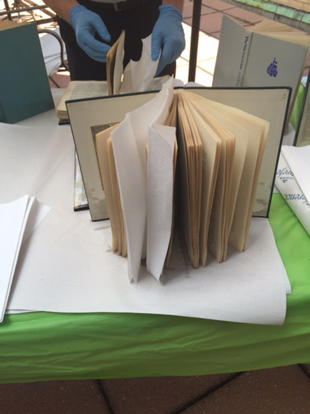 A wet book is interleaved with plain paper towels and stood up to dry. 
